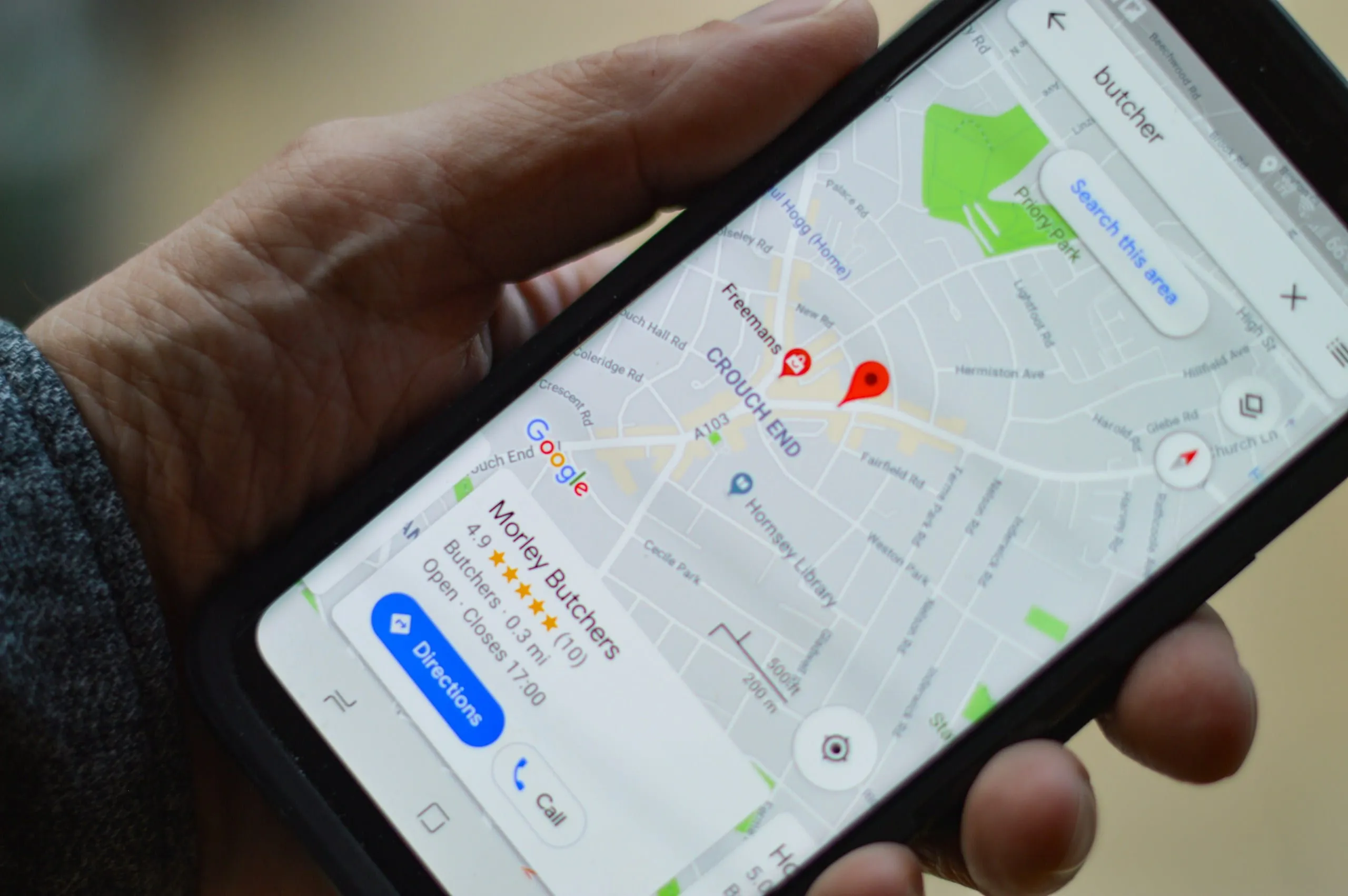 Main tenant un smartphone qui affiche Google Maps avec un commerce local épinglé