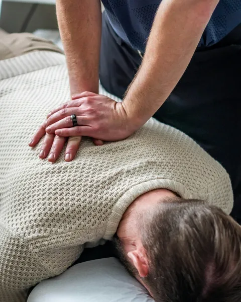 Thérapeute en séance, les mains sur le dos d’un patient